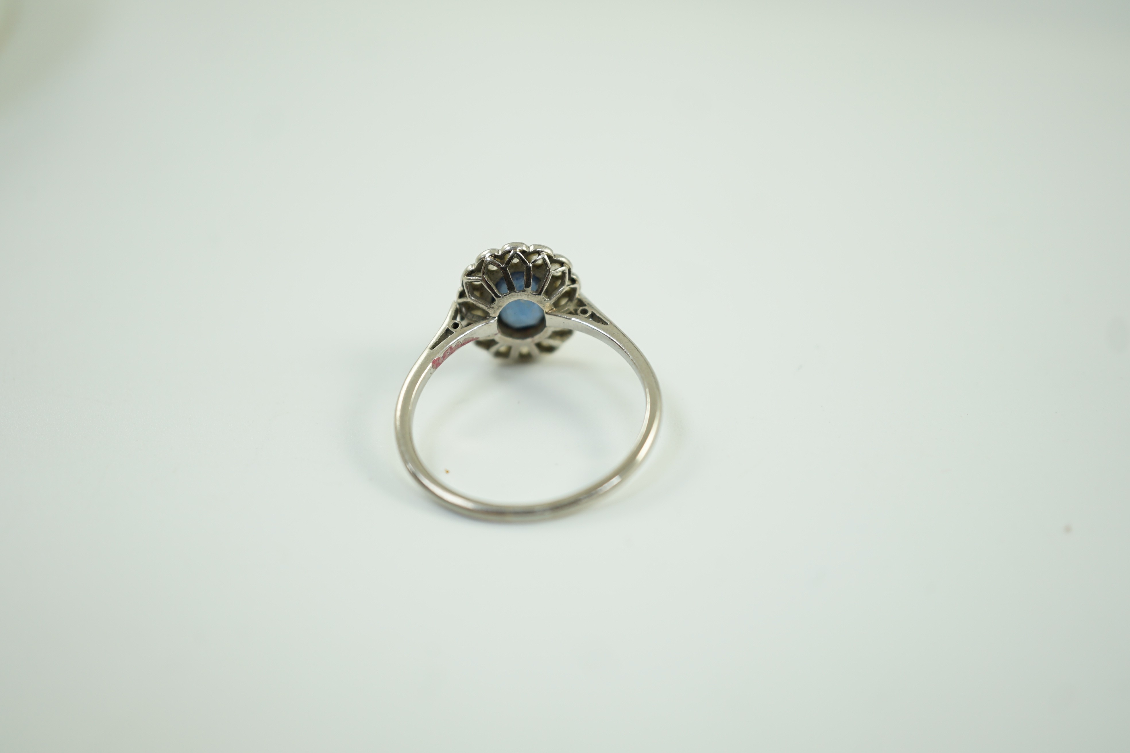 A white metal, sapphire and diamond set oval cluster ring, size M/N, gross weight 2 grams.